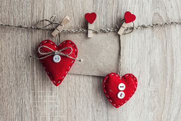 blank paper card with hearts hanging on wooden background