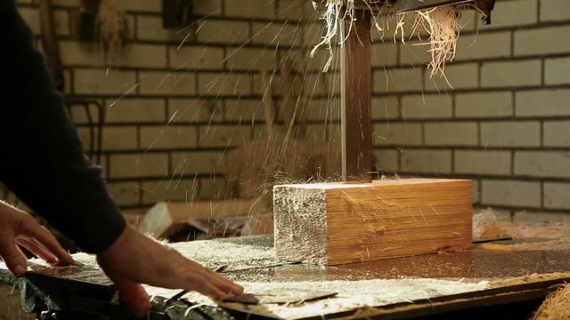 Clog maker sawing wood with a band saw