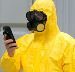 Worker in protective chemical suit checking radiation with geiger counter.