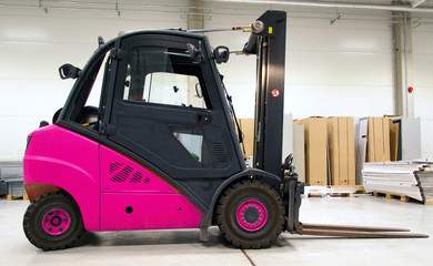 Pink forklift loader in the large modern warehouse.