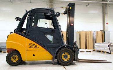 Yellow forklift loader in the large modern warehouse.