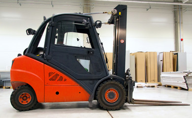 Orange forklift loader in the modern warehouse.