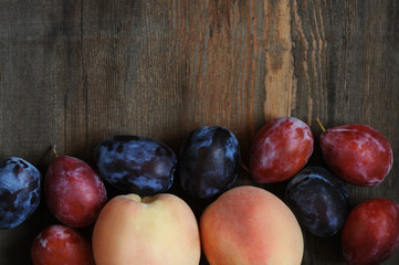 Peaches and plums on dark wooden table.