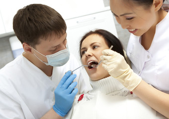 Fototapeta premium Young woman keeping her mouth open while dentist examining it