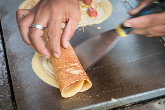 Seller rolling Khanom Tokyo thin flat pancake filled with sweet