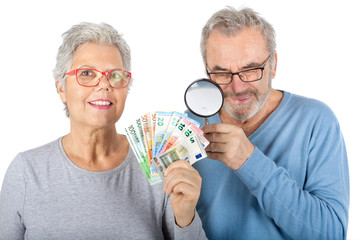Seniorenpaar mit Geld und Lupe