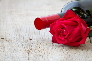 Rose with red wine bottle on wooden. Valentine's day, anniversar