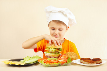 Young smiling chef shows how to cook a hamburger