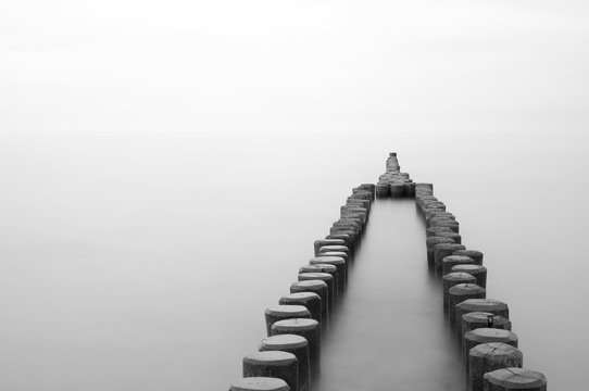 Fototapeta old wooden breakwater at the beach, black and white, long time exposure, German Baltic Sea Coast, Europe