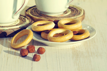 Two cups for tea with fragrant bagels on a white wooden background
