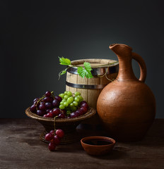 bowl with red wine pitcher with a barrel and grapes