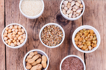 Obraz na płótnie Canvas Bowls of various legumes and seeds. Lentils, sesame seeds, pistachio nuts, flaxseed, raisins, peanuts, chickpeas. 