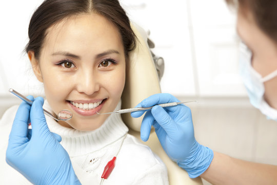 Smiling patient looking at camera while dentist examining it