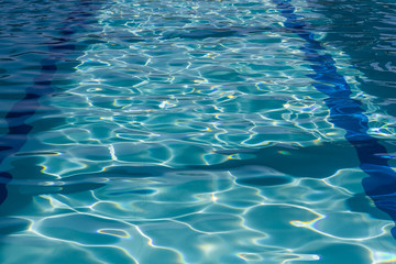 Background of rippled pattern of clean water in a blue swimming pool