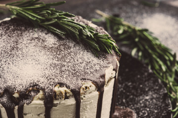 Creamy cake with chocolate glaze on the rustic background. Toned image.