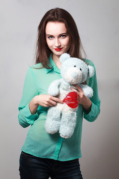 Girl in the turquoise shirt with a blue teddybear and a lollipop in the shape of heart