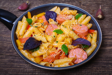 pasta with sausage, peppers, cheese and herbs on a wooden background