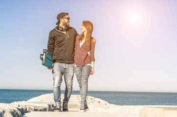 Couple of skaters in love walking and smiling at the beach - Concept about people, sport, lifetyle...