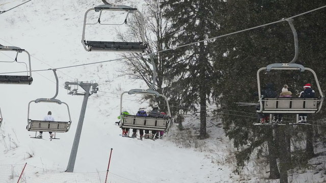 Ski lift chairs on winter day.Modern chair ski lift in ski resort.people ride the ski chair lift up the mountain.Ski chair lift with skiers