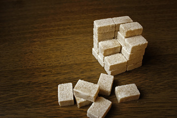 Brown sugar cubes on wooden background