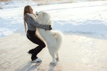 young Figure skating woman with dog Samoyed at the frozen lake in the winter