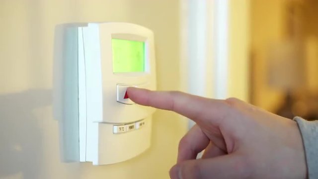 Person adjusting climate control thermostat in home.