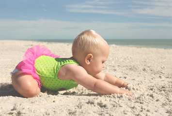 Fototapeta na wymiar Cute Baby Girl Playing in the Sand at the Beach