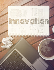 work place - table with notebook with note about: innovation