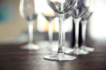 Empty wine glasses with bottle on wooden table against blurred background