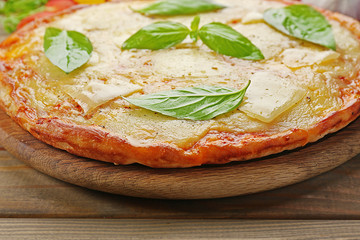 Tasty pizza decorated with basil and vegetables on wooden background, close up