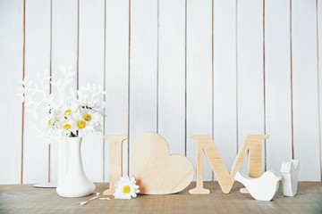 Wooden letters with heart and flowers on white wall background