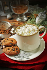 Mug of hot chocolate with marshmallows, fir tree branch on wooden background