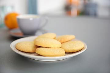 Cup of coffee and plate of cookies on the table against unfocused background