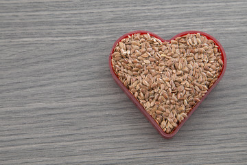 Diet healthcare healthy food. Raw flax seeds linseed heart shaped on wooden board background.