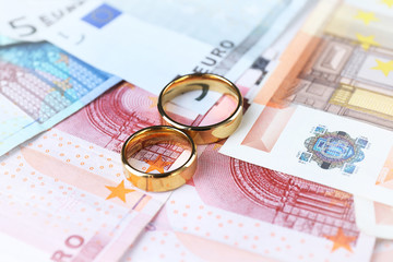 Golden wedding rings on euro banknotes background. Marriage of convenience