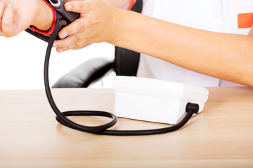 Doctor sitting behind the desk holding blood pressure gauge