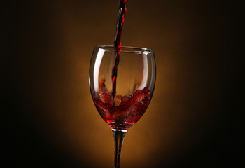 Wine pouring in glass on brown background