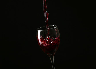 Wine pouring in glass on black background