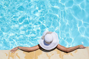 beautiful young woman in the swimming pool on a sunny summer day - obrazy, fototapety, plakaty