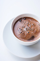 White cup of coffee on white table