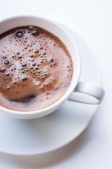 White cup of coffee on white table