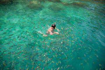 Man swims among the fish in a mask and a snorkel, Thailand