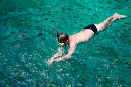 Man swims among the fish in a mask and a snorkel, Thailand