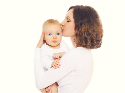 Portrait of happy loving mother kissing her baby on a white back