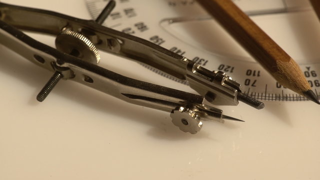 A close view of a vintage engineering concept setting with compasses and a pencil