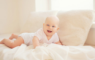 Happy smiling baby crawls at home in white room near window