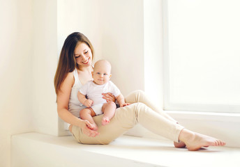 Happy young mother with baby at home in white room