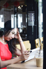 Cafe city lifestyle woman on phone drinking coffee texting text message on smartphone app sitting indoor in trendy urban cafe. Cool young modern mixed race Asian Caucasian female model in her 20s.