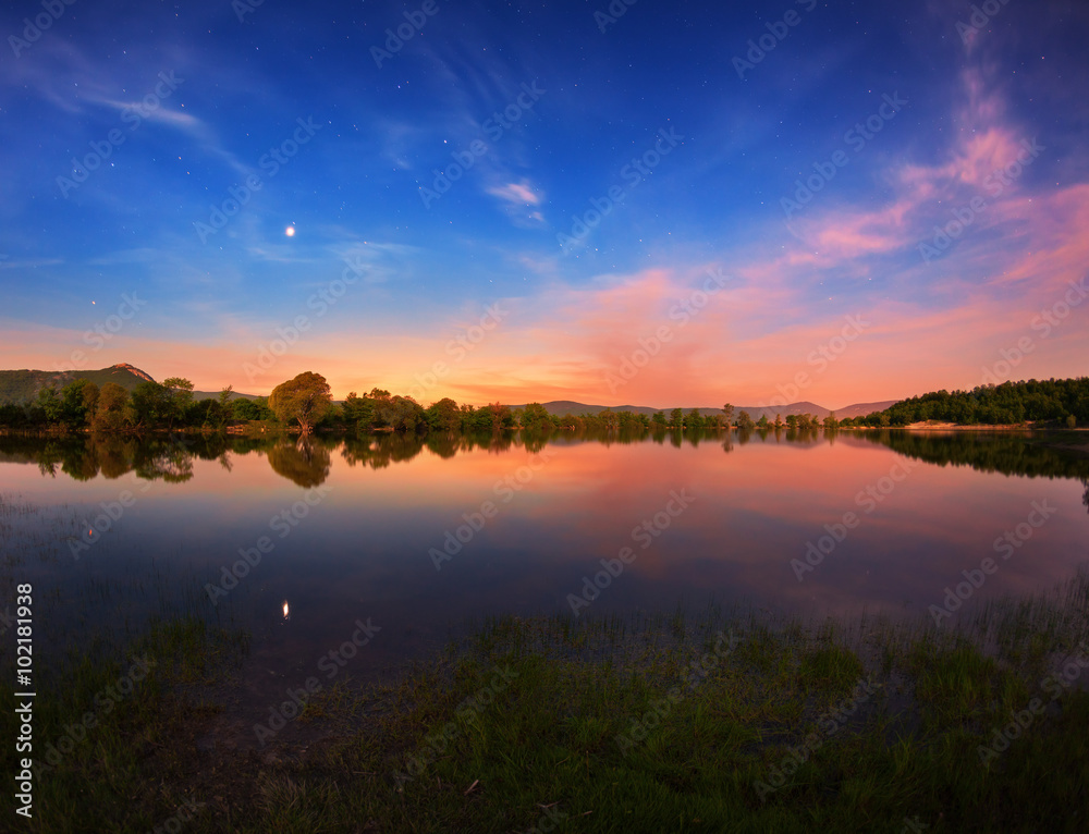 Wall mural beautiful night landscape on the mountain lake with stars and reflected clouds in water in spring. c