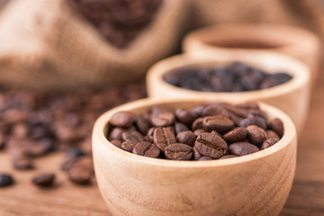 Coffee powder and coffee beans in the wood bolws, background is the coffee bags on the wooden table
